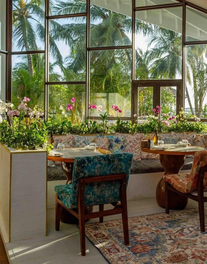 An orchid-lined dining nook at Vista del Mar, with floor-to-ceiling windows onto the palm garden