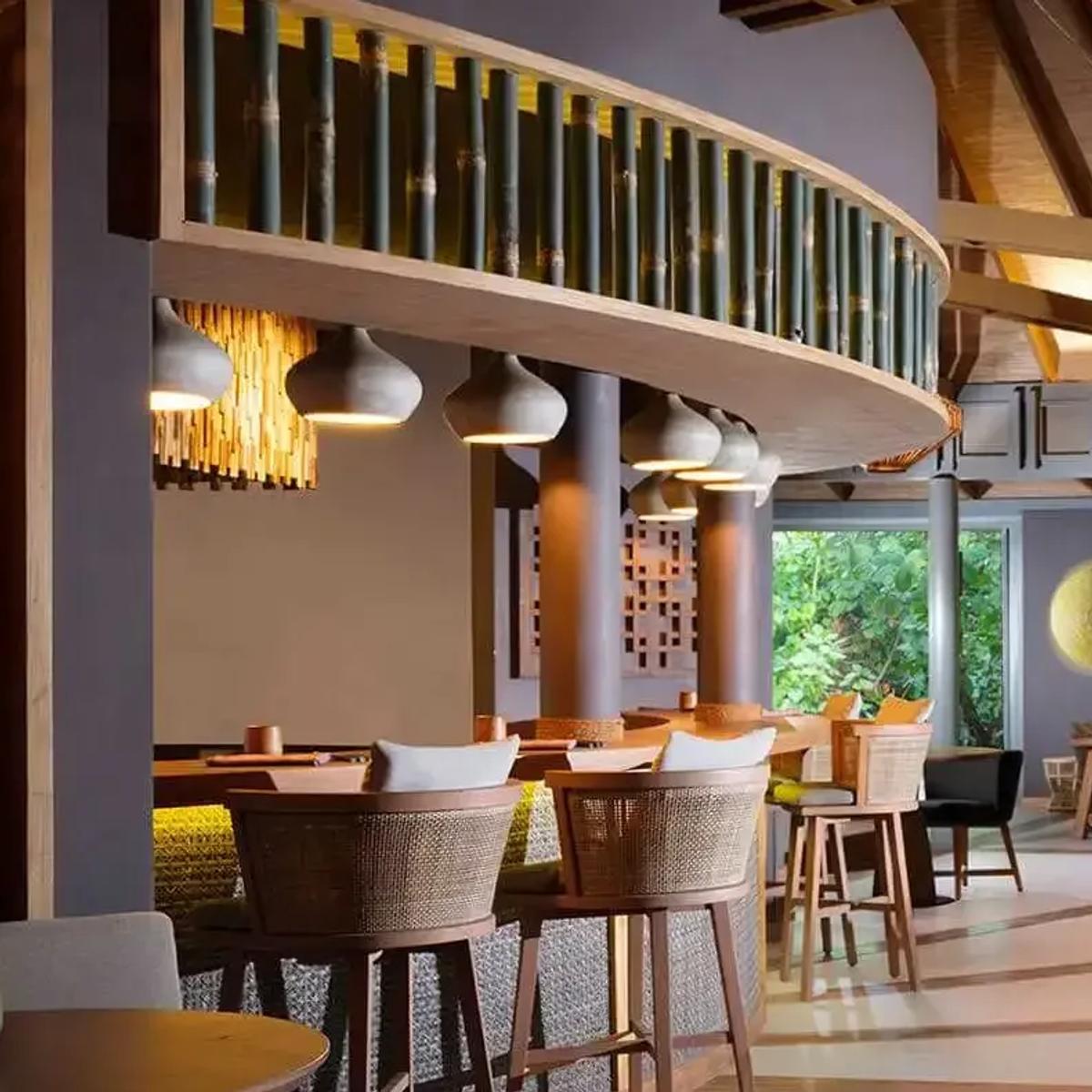 Interior of Onu's bamboo-domed dining pavilion, an open kitchen and dining counter set beneath woven ceiling lanterns
