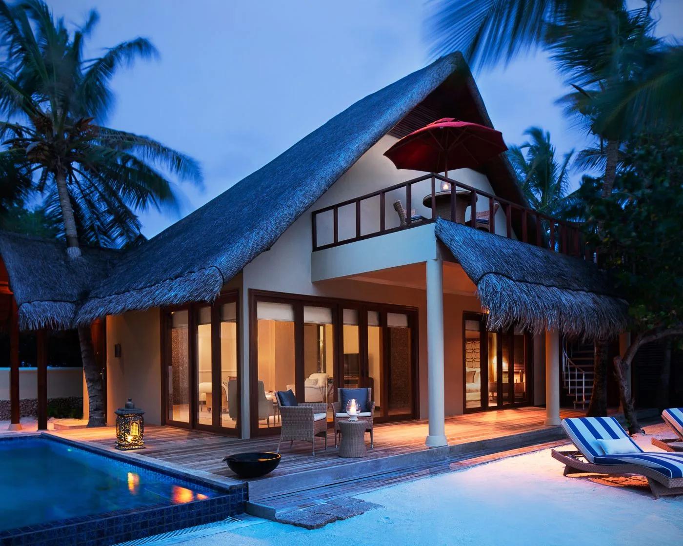 A One Bedroom Sunset Beachfront Suite with Pool at dusk, its upper balcony lit above the private pool