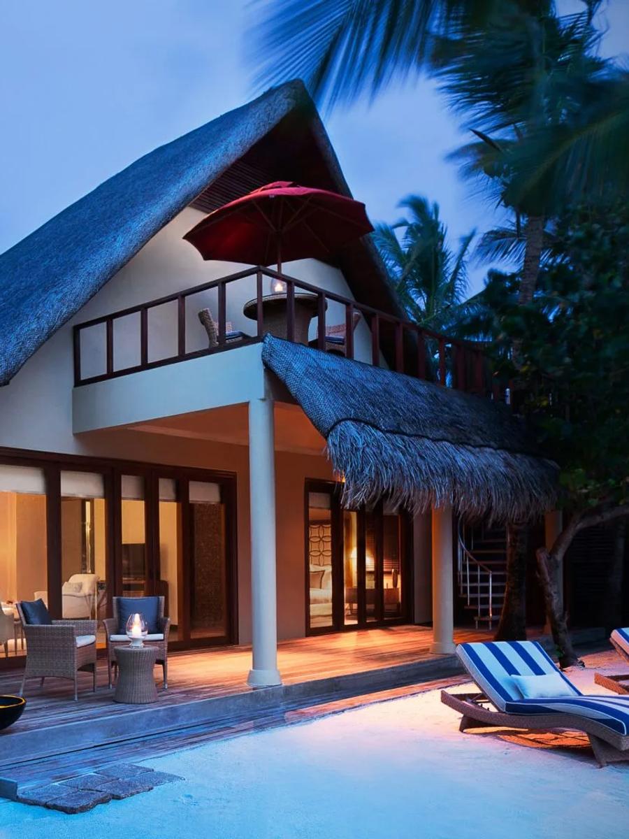A One Bedroom Sunset Beachfront Suite with Pool at dusk, its upper balcony lit above the private pool