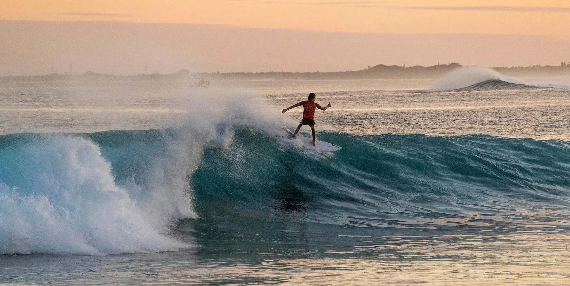A surfer riding a wave at Chicken's Break, directly off Kuda Villingili island