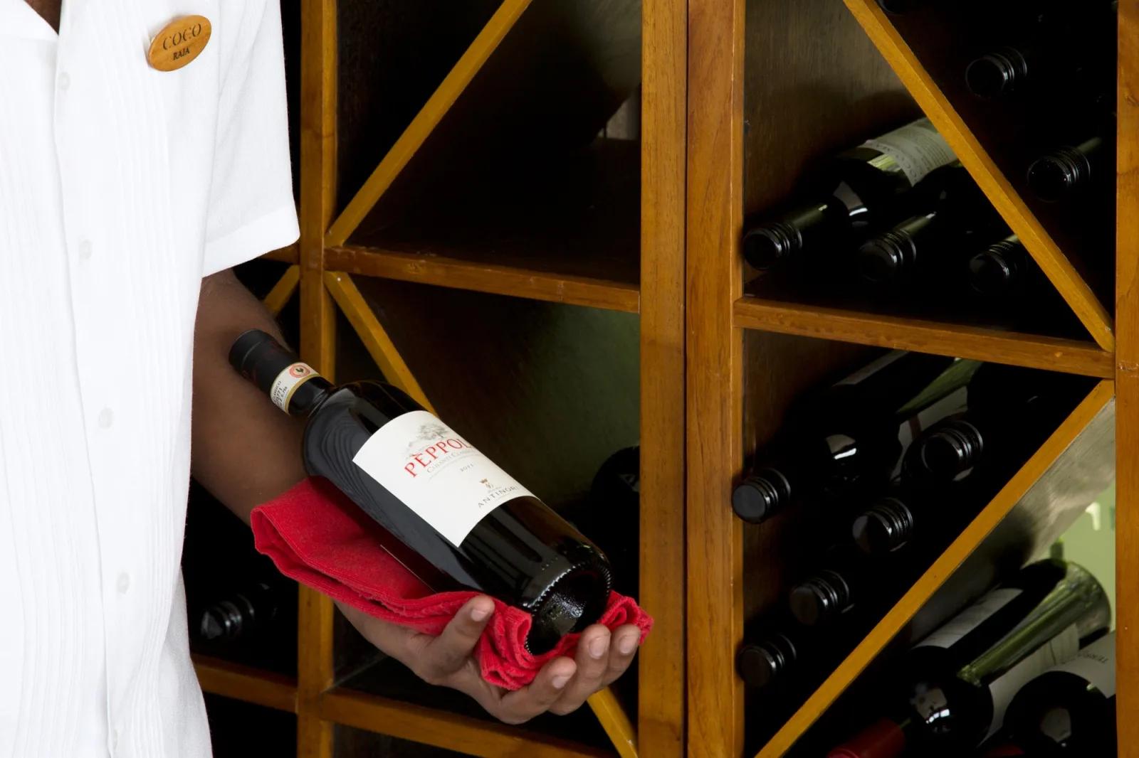 A staff member wearing a Coco name badge selecting a bottle of wine from the Wine Loft's racks