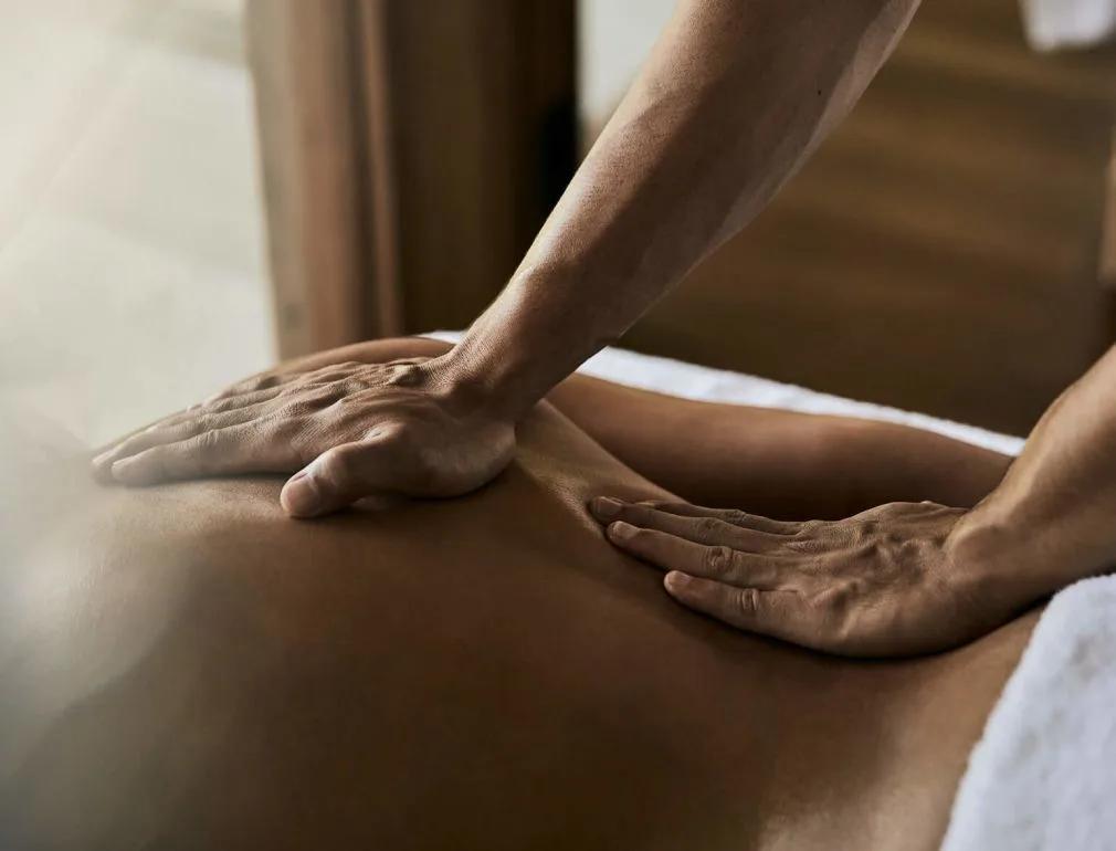Close-up of a therapist's hands performing a back massage in warm light
