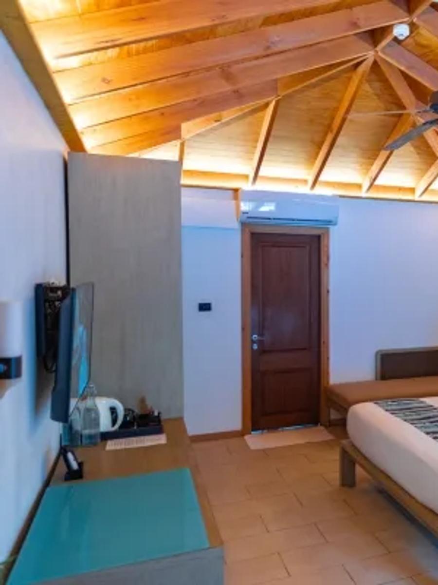 Adjacent Beachfront Villa bedroom, with an exposed wood-beam ceiling and bench seating