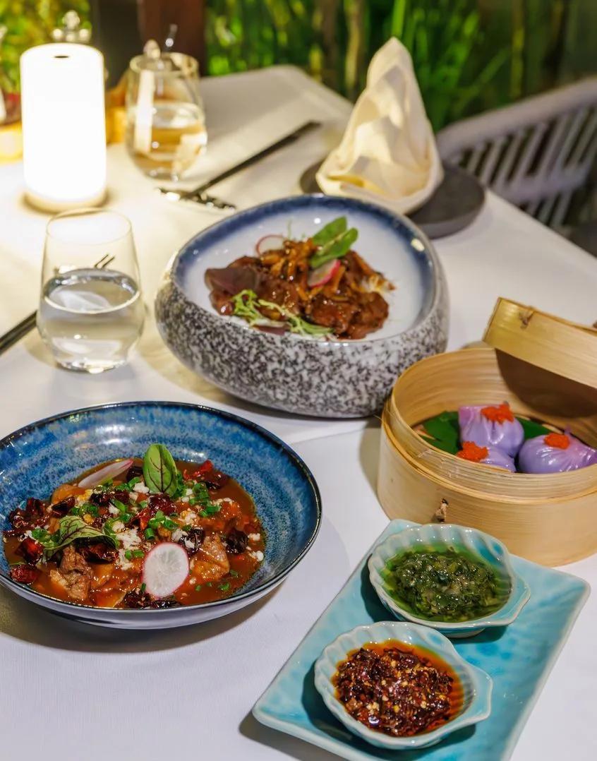 A spread of pan-Asian dishes at Soyi, including a bamboo steamer of dumplings and chilli condiments