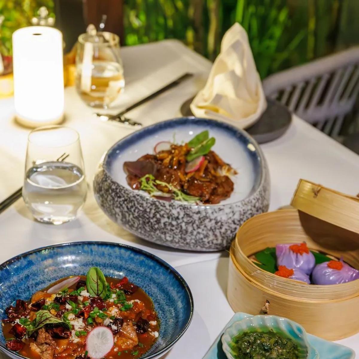 A spread of pan-Asian dishes at Soyi, including a bamboo steamer of dumplings and chilli condiments
