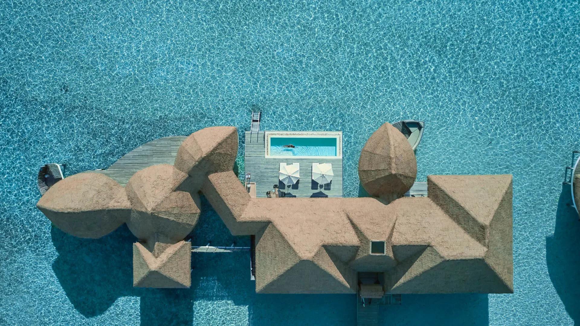 Aerial view directly above a COMO Villa's thatched roof and private plunge pool over the lagoon