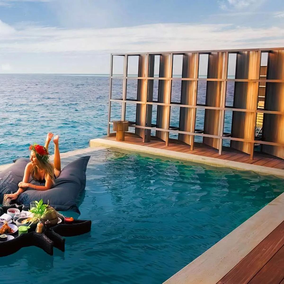 A floating breakfast tray anchored in an Ocean Residence's pool, a guest reclining on cushions beside it