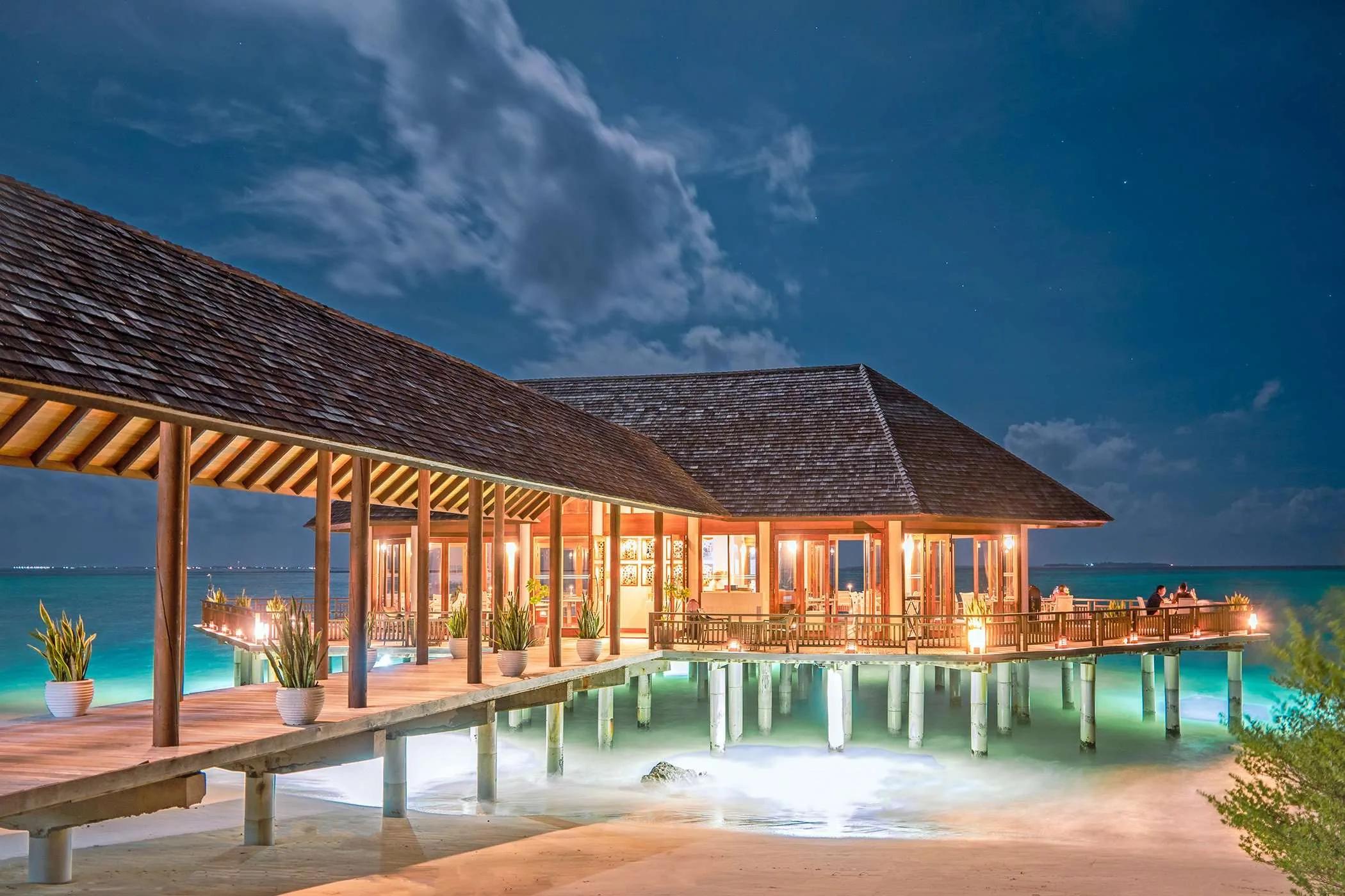 Samsara Asian Fusion restaurant lit at night, its overwater dining room over the lagoon