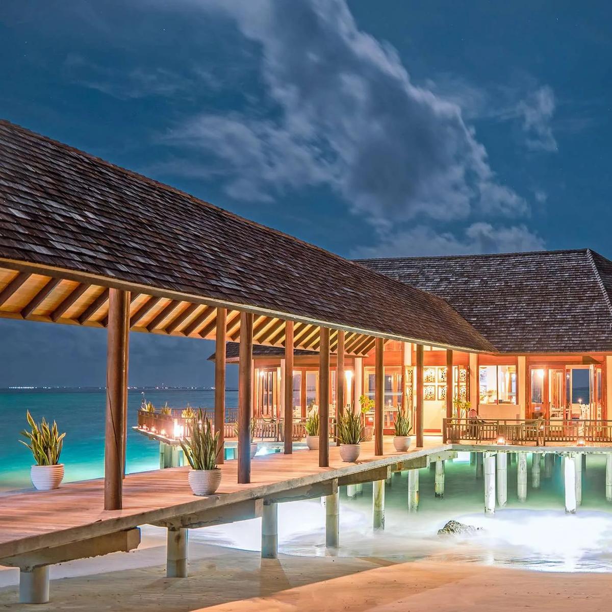 Samsara Asian Fusion restaurant lit at night, its overwater dining room over the lagoon