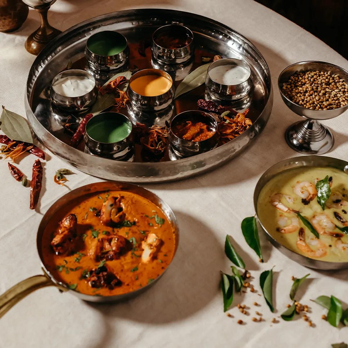 A silver thali tray of curries, raita and spiced condiments laid out for Indian dining at Taste of India