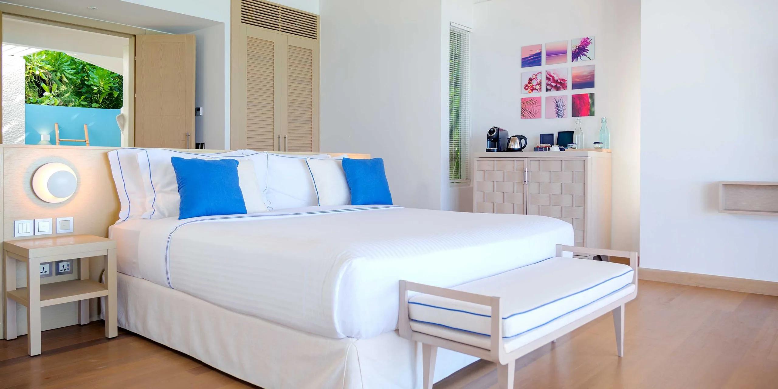 One of two bedrooms in a Two-Bedroom Beach Suite with Pool at Baglioni Maldives, with a wall of framed ocean and nature photographs