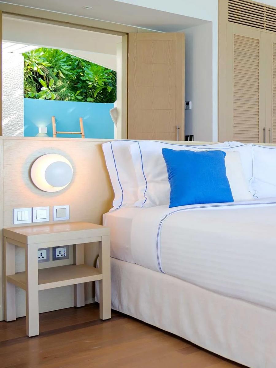 One of two bedrooms in a Two-Bedroom Beach Suite with Pool at Baglioni Maldives, with a wall of framed ocean and nature photographs
