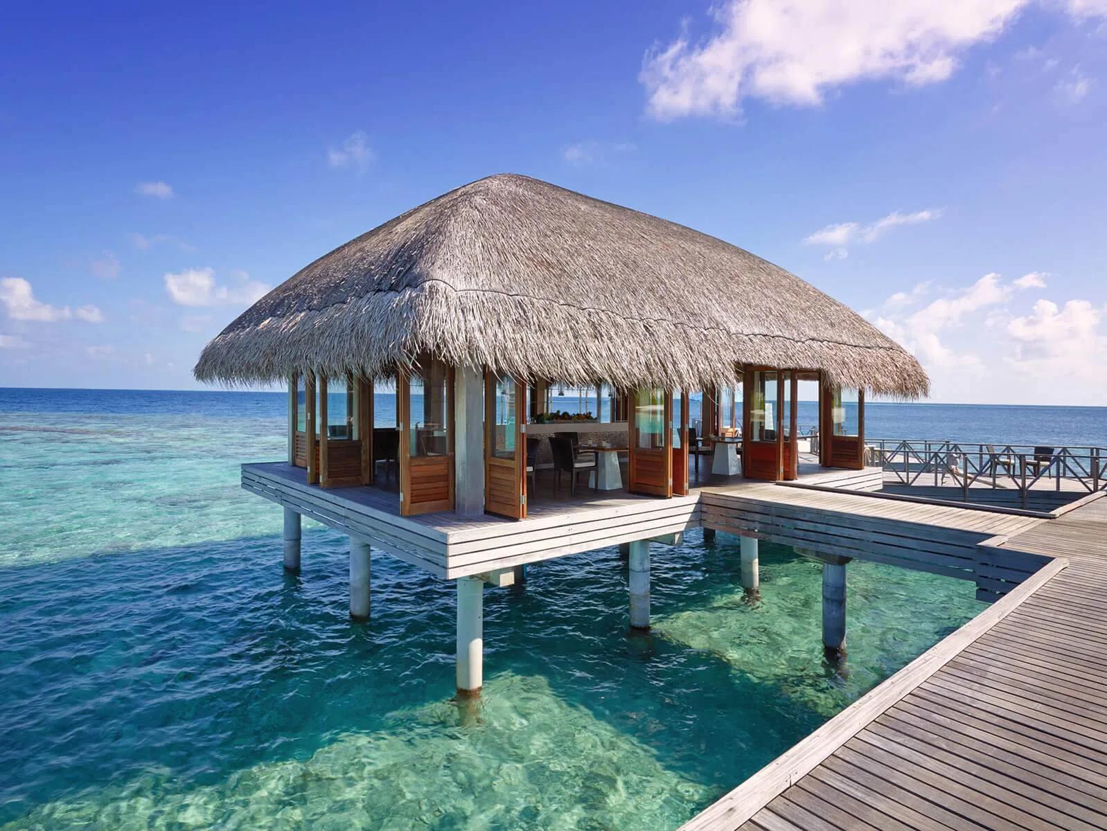 Raw restaurant's overwater dining room, glass doors folded open to the lagoon