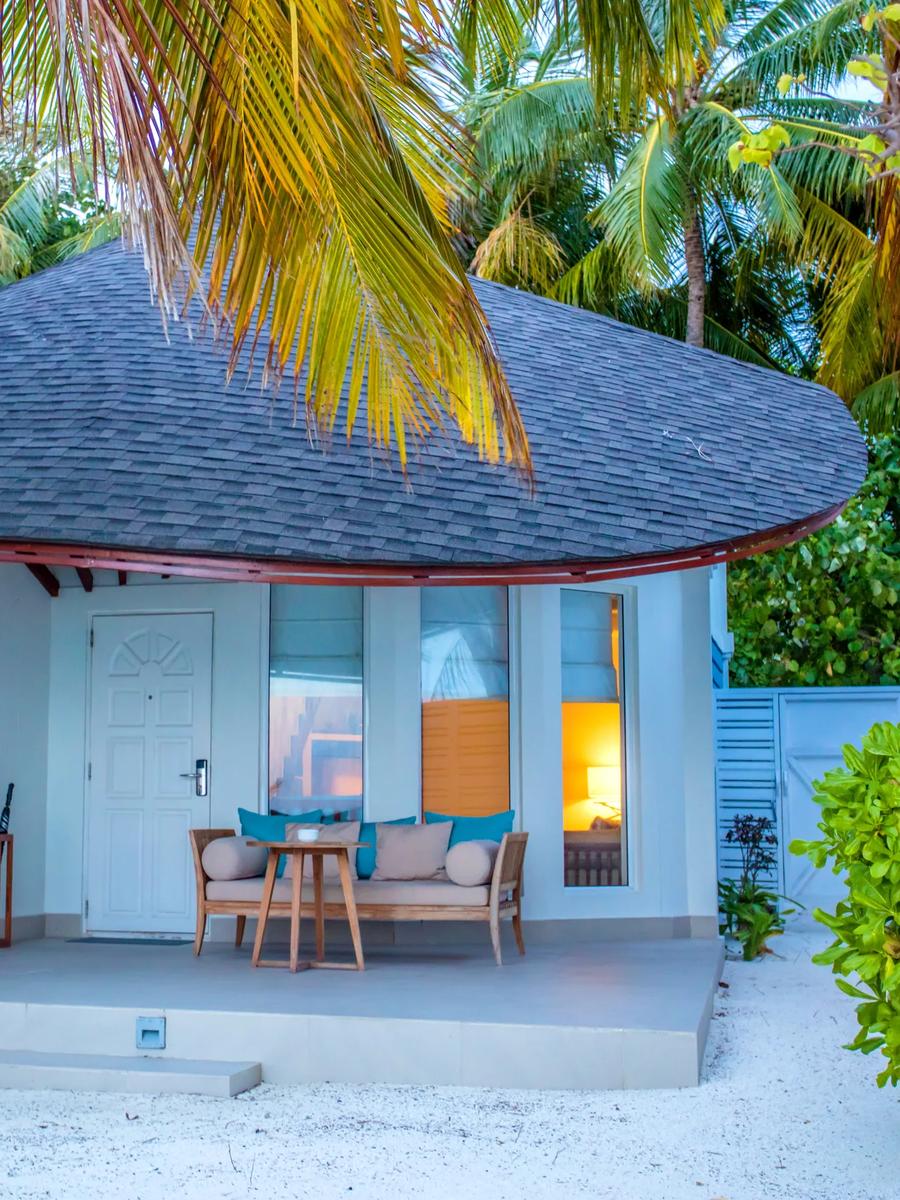 A Duplex Beach Villa's shingled roof and terrace under coconut palms at dusk