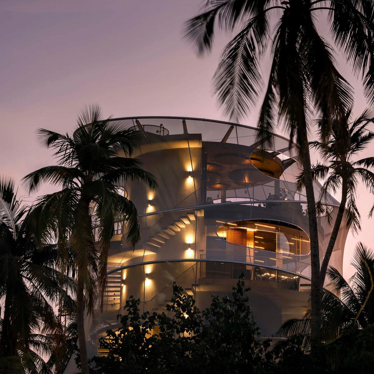 The spiral tower housing Tavaru's teppanyaki dining and wine cellar, lit at dusk and framed by palm trees