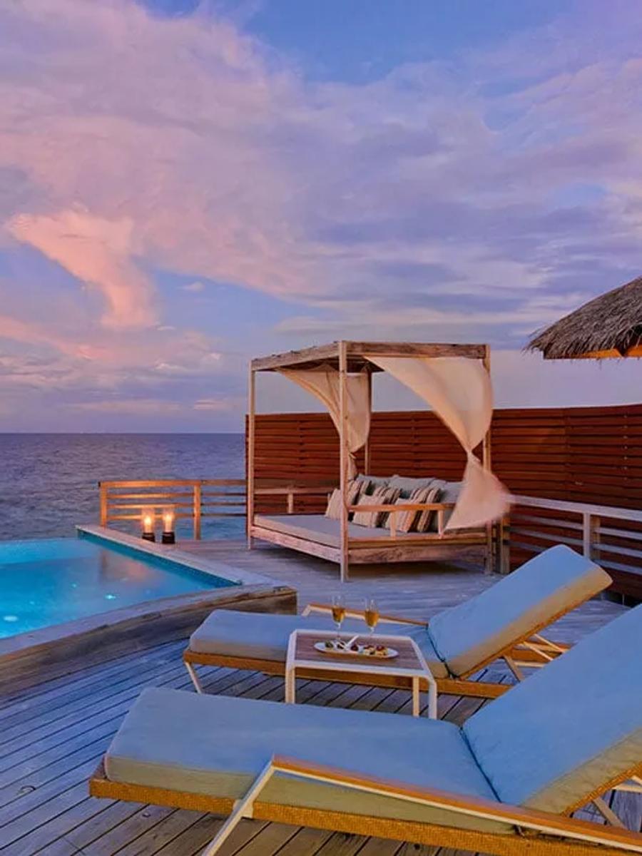 A Water Pool Villa's private infinity pool at dusk, deck lanterns lit and open ocean stretching to the horizon