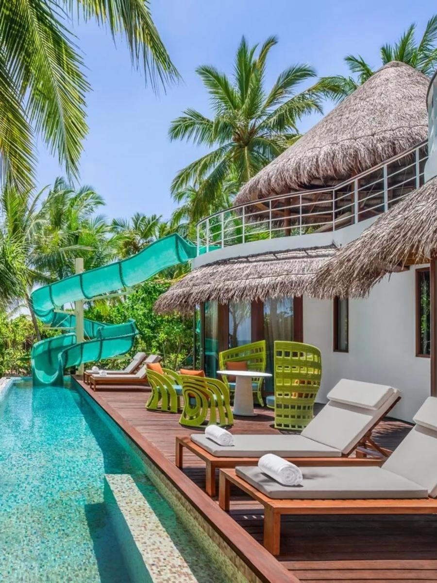 A two-storey Oasis Beach villa at W Maldives with a water slide running from the upper deck into the villa's private pool