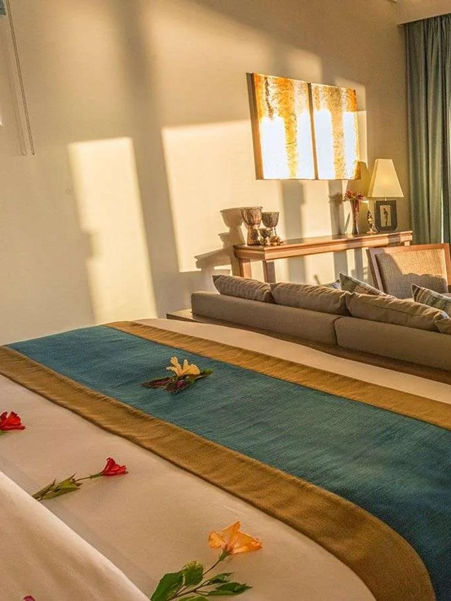 An Ocean Villa's bedroom opening onto its overwater deck, with a dining table set for two above the lagoon