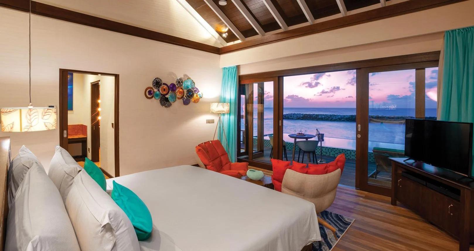 A Sunset Water Villa with Pool's bedroom, its deck and pool catching the day's last light over the lagoon
