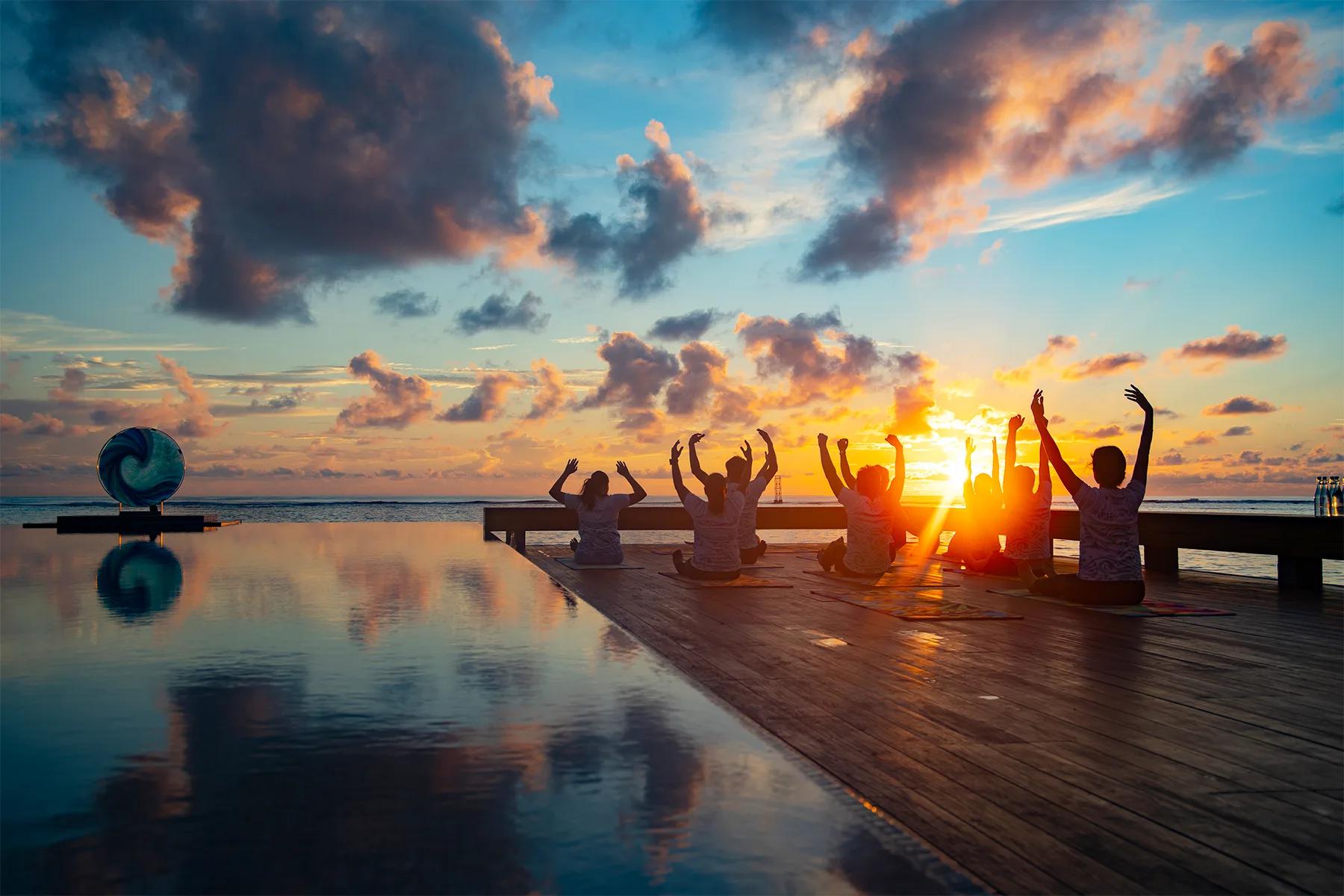 A guest practising yoga on the beach at sunrise