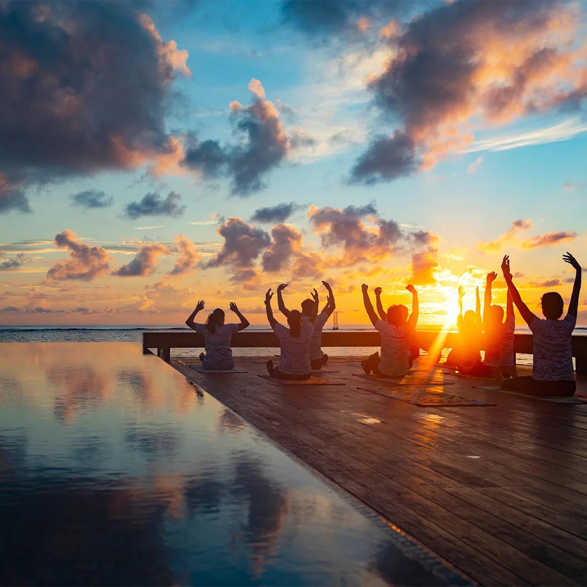 A guest practising yoga on the beach at sunrise