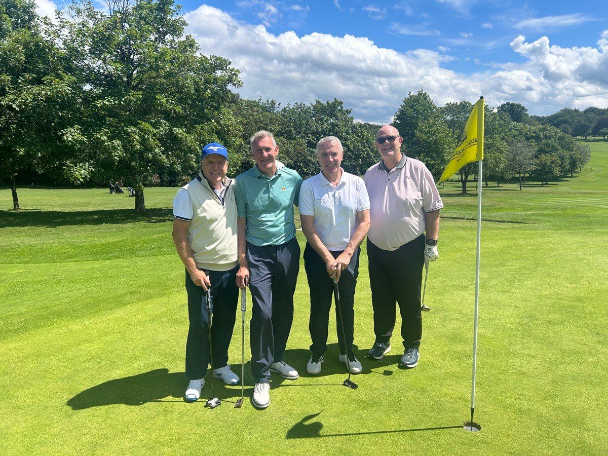 A group beside the flag on a sunlit green