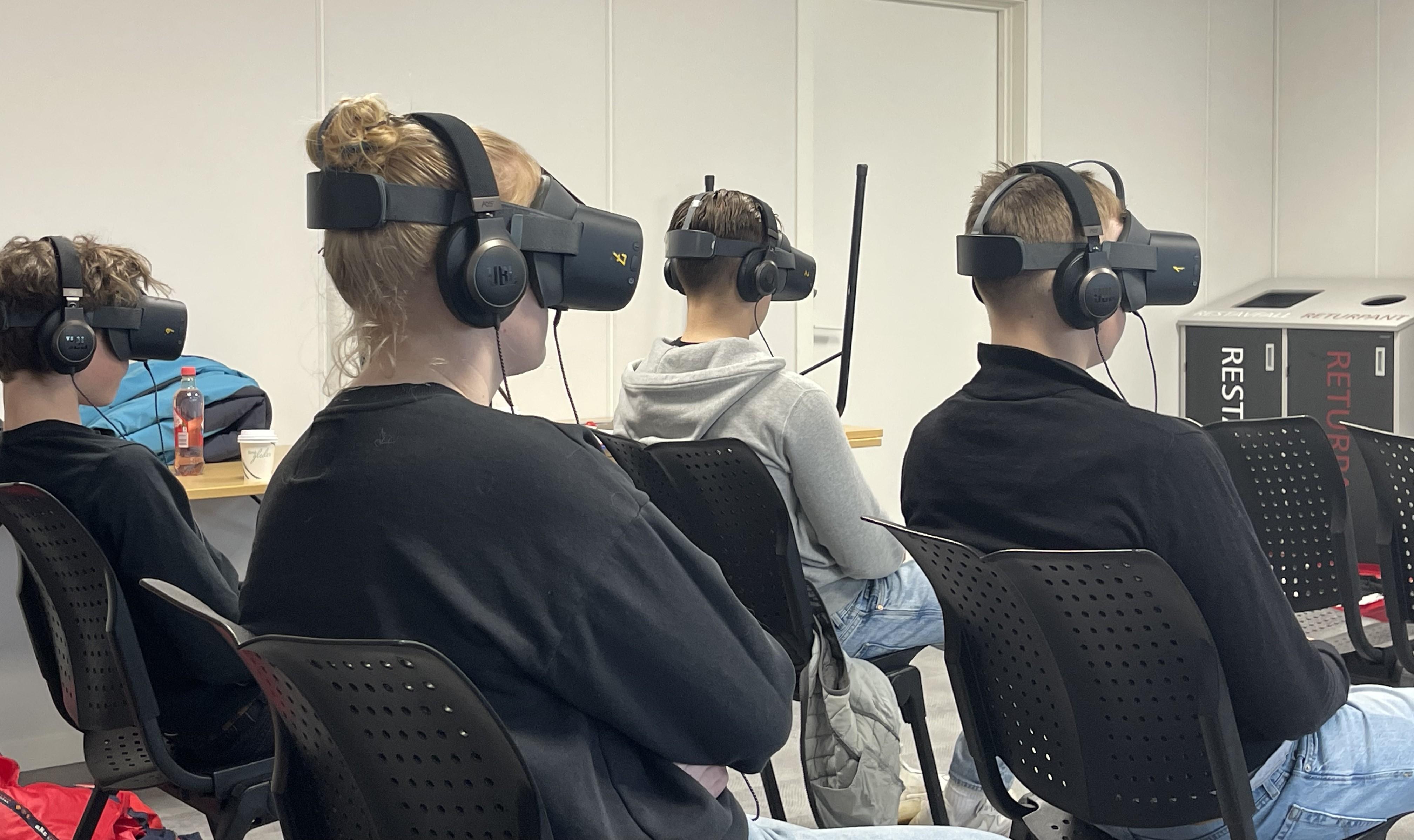 Bildet viser ungdom som sitter på stoler med VR-briller og headtset på hodet.