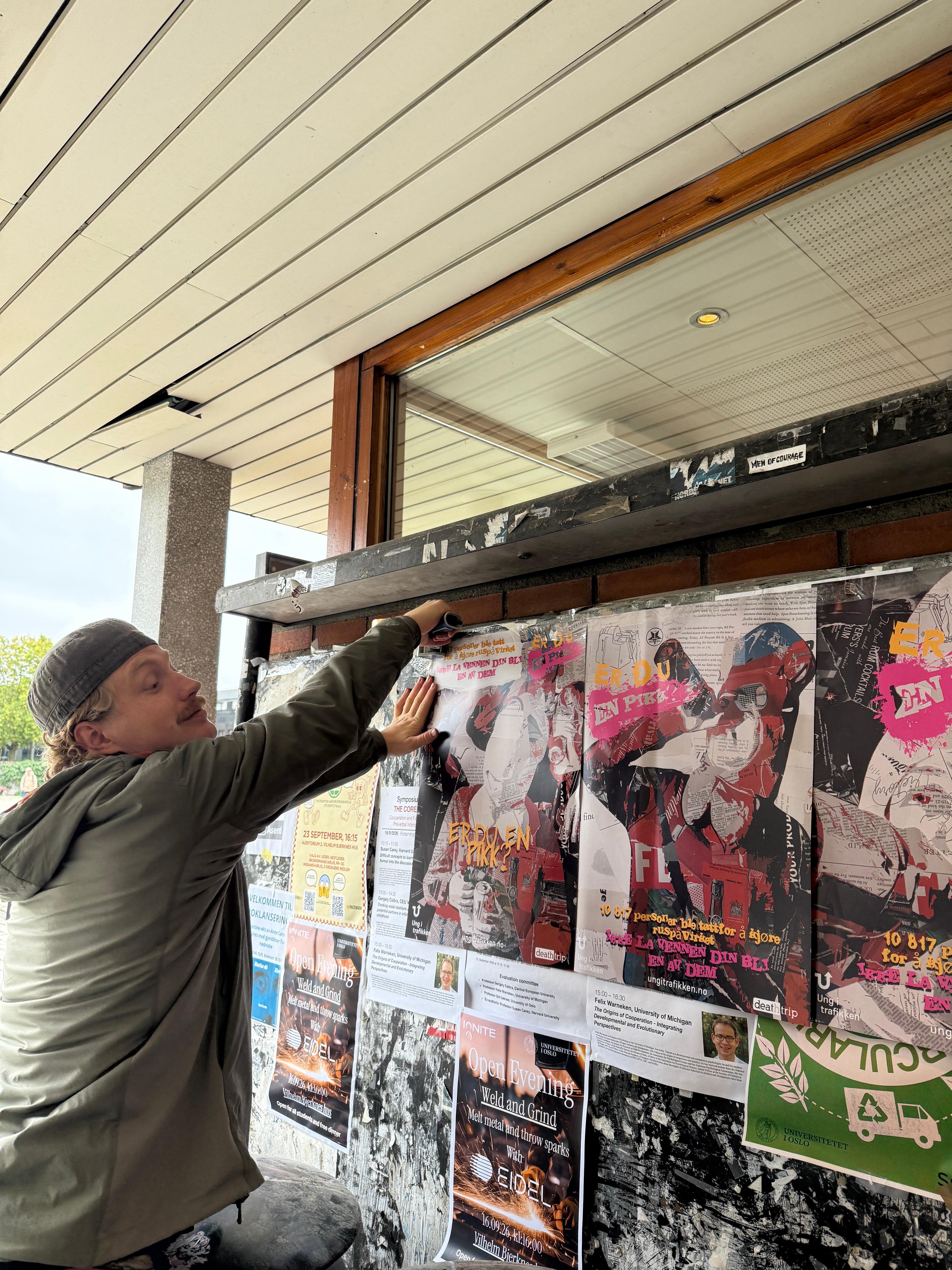 Gutt som henger opp plakater