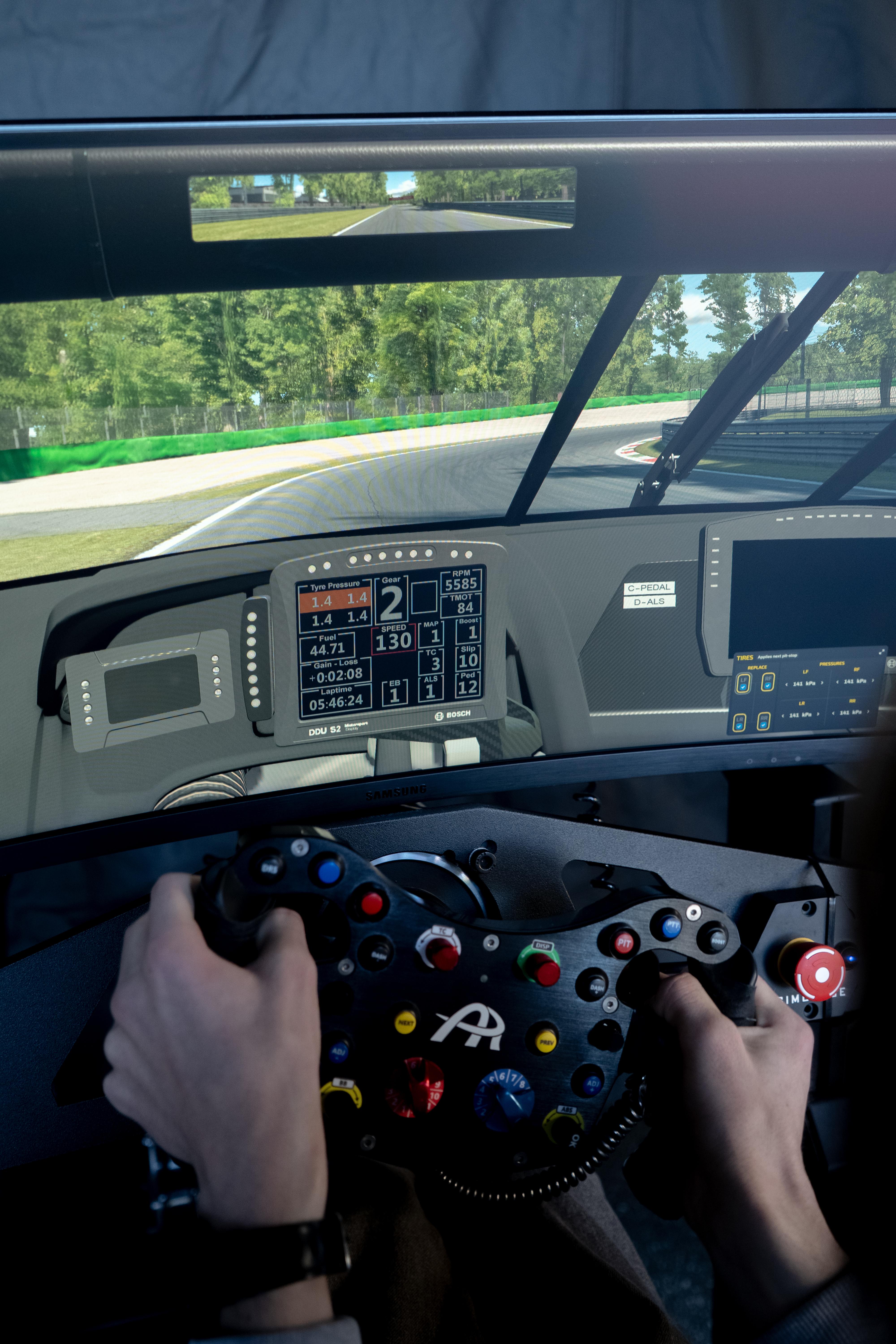 skjerm på kjøresimulator viser racerbanen. Rattet har mange knapper.