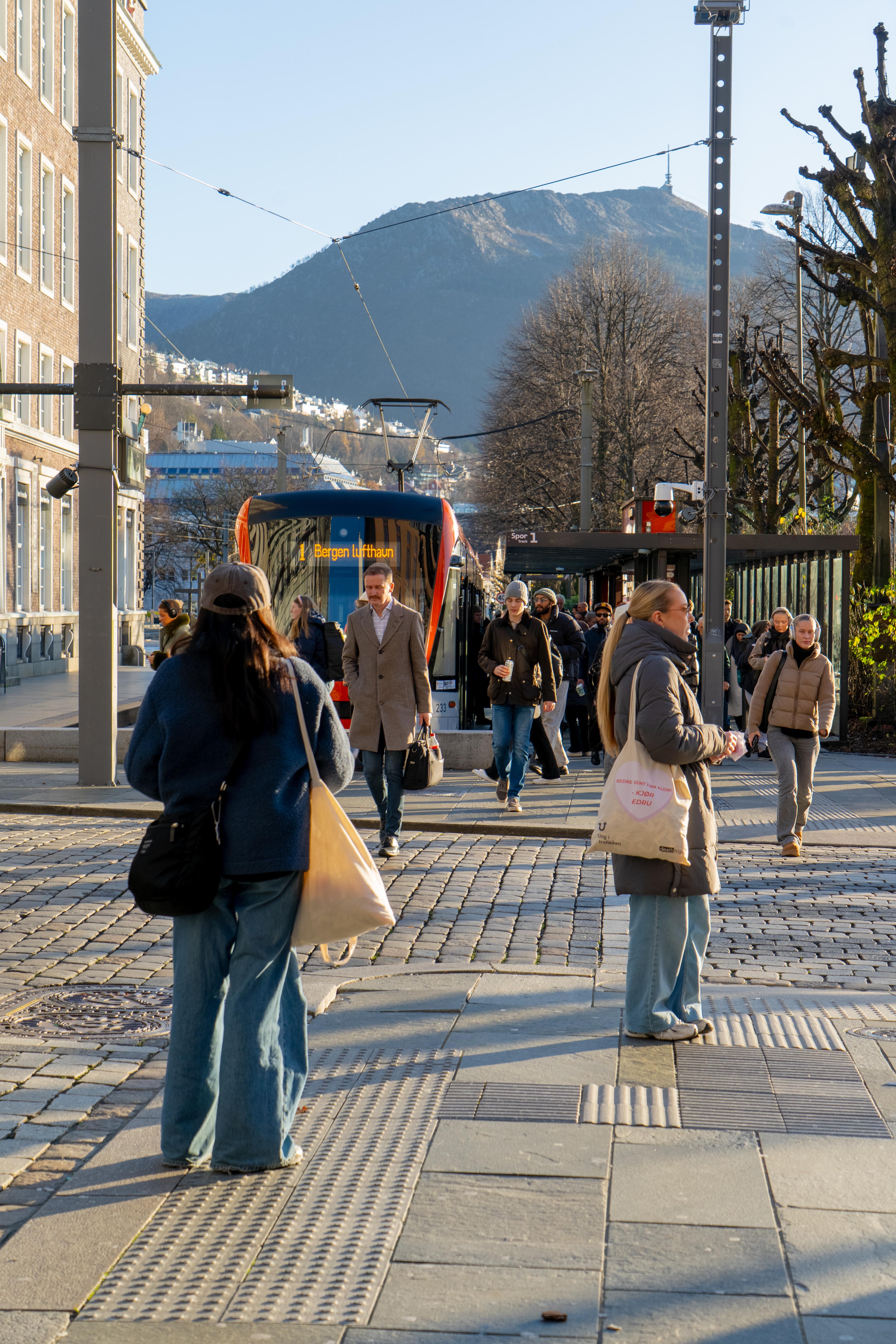 To personer som deler ut kjærlighet på pinne med budskapet "bedre sent enn aldri - kjør edru" til folk som går av bybanen