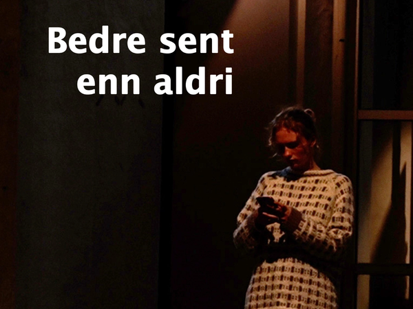 Ung jente som står utenfor kino med mobilen i hånden i mørket og venter på daten sin som aldri kommer.