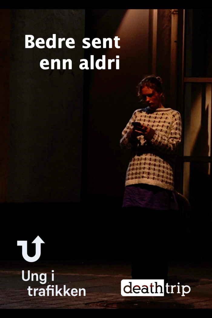 Jente som står utenfor kino i mørket og sjekker telefonen