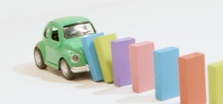 En grønn bil som kjører inn i noen dominobrikker