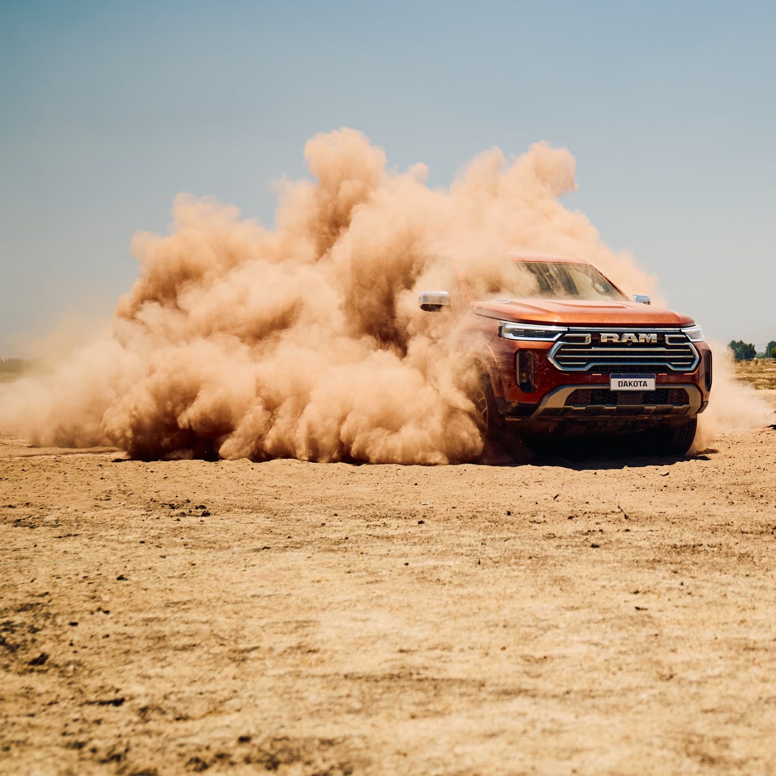RAM Dakota driving across a dry plain, kicking up a plume of dust