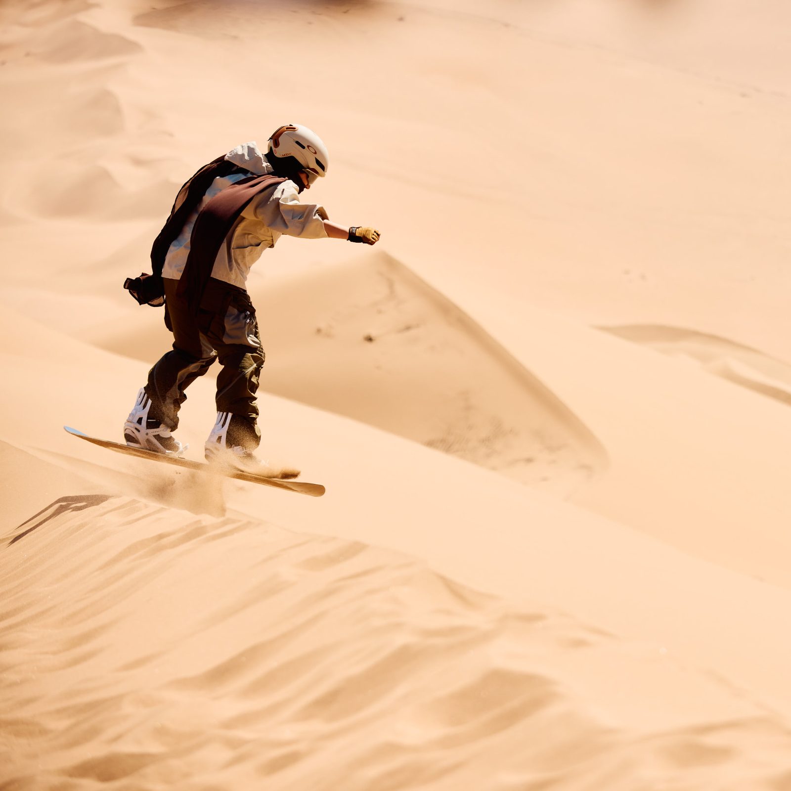Sandboarder airborne off the crest of a desert dune