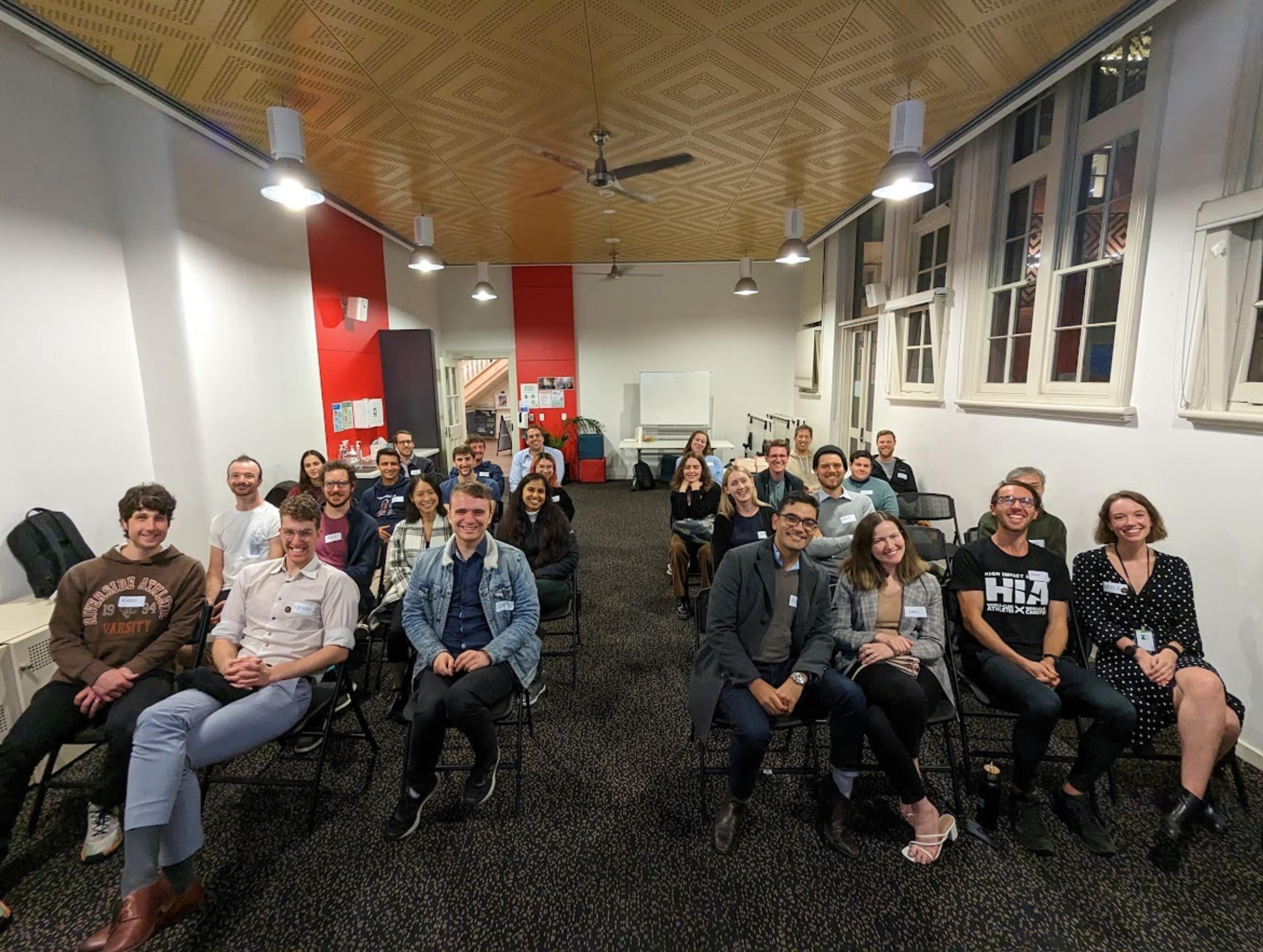 a photo of 25 people smiling, sitting in chairs