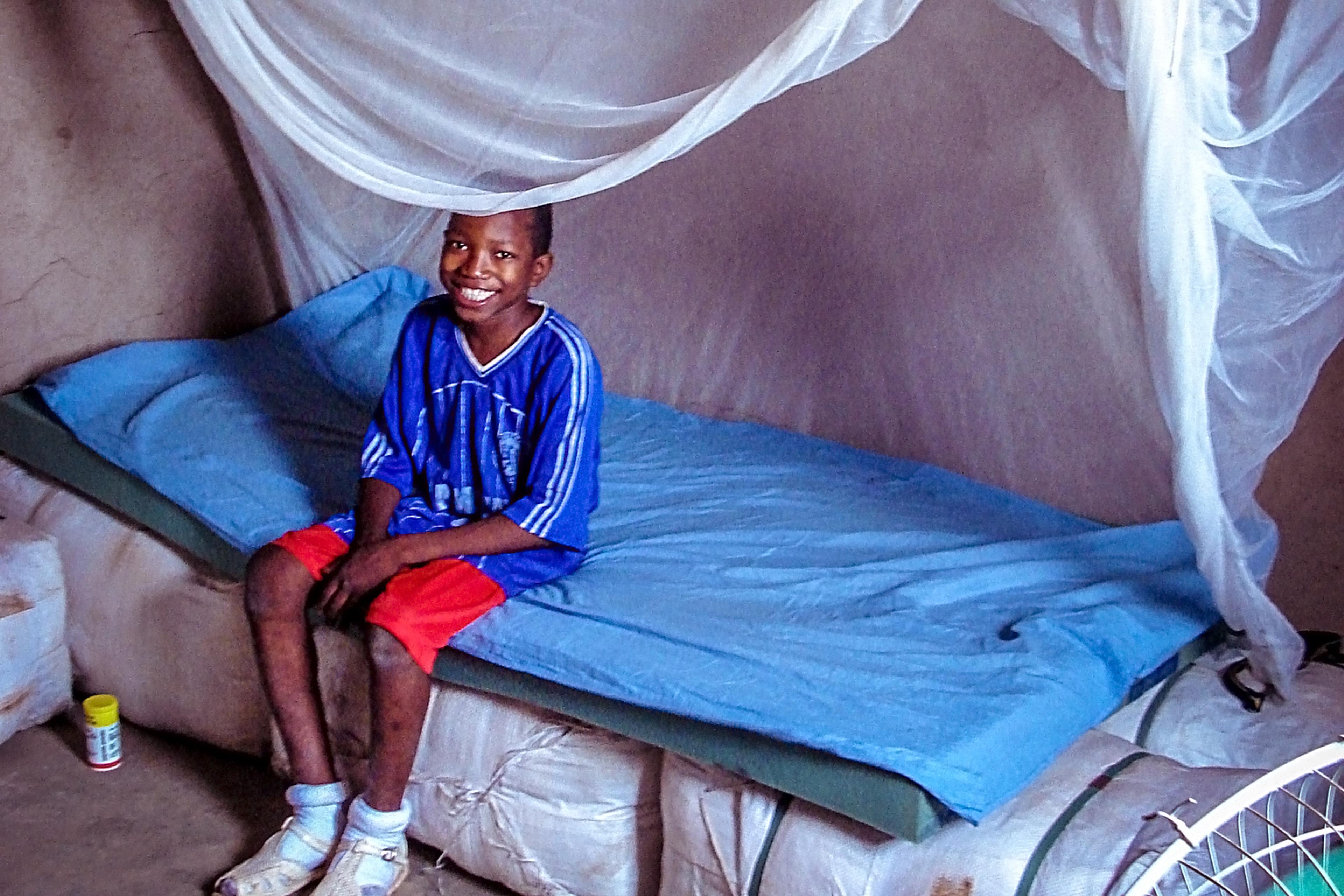 Boy sitting on a bed with a net