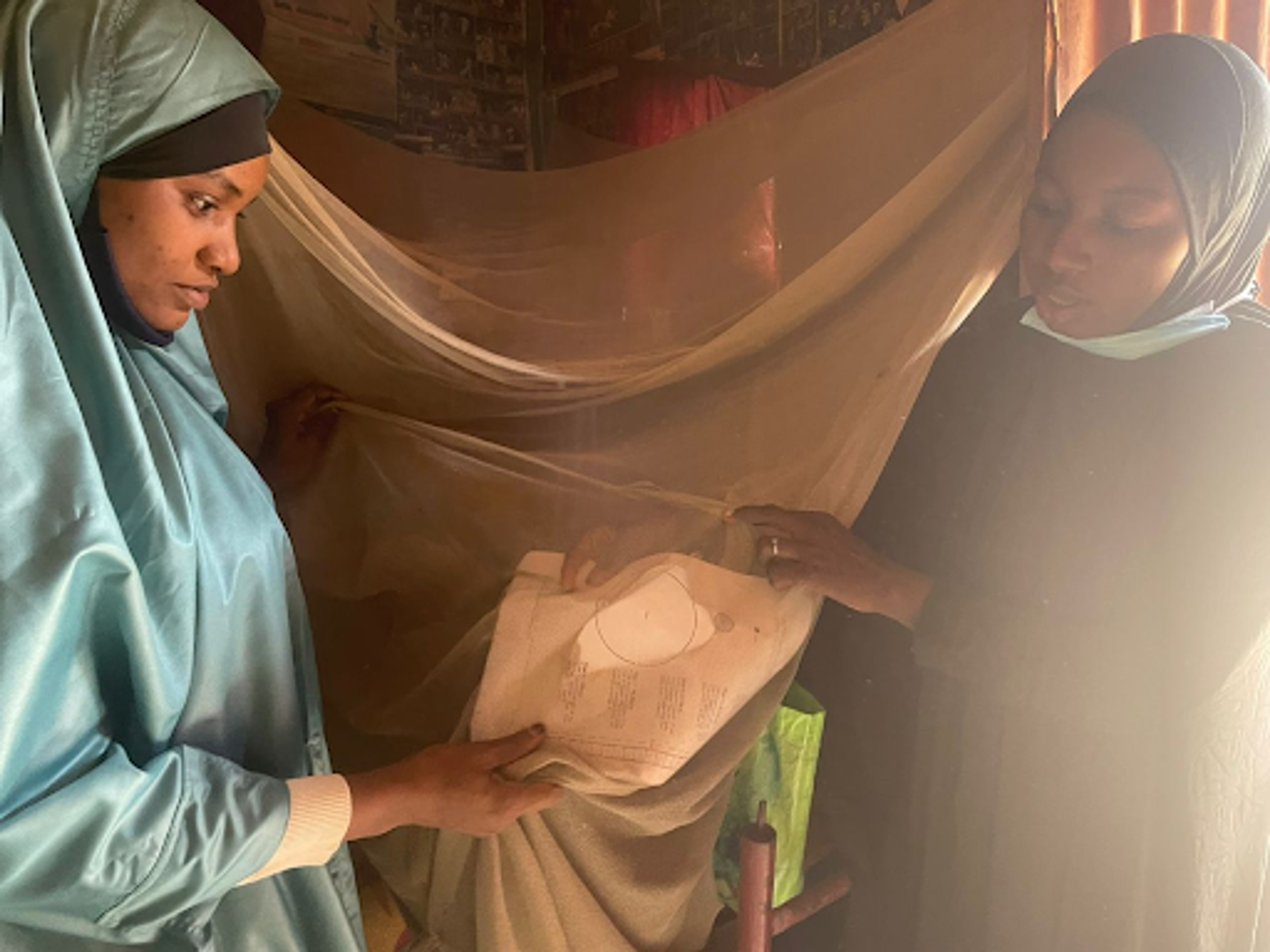 Two people see a hole in a malaria net