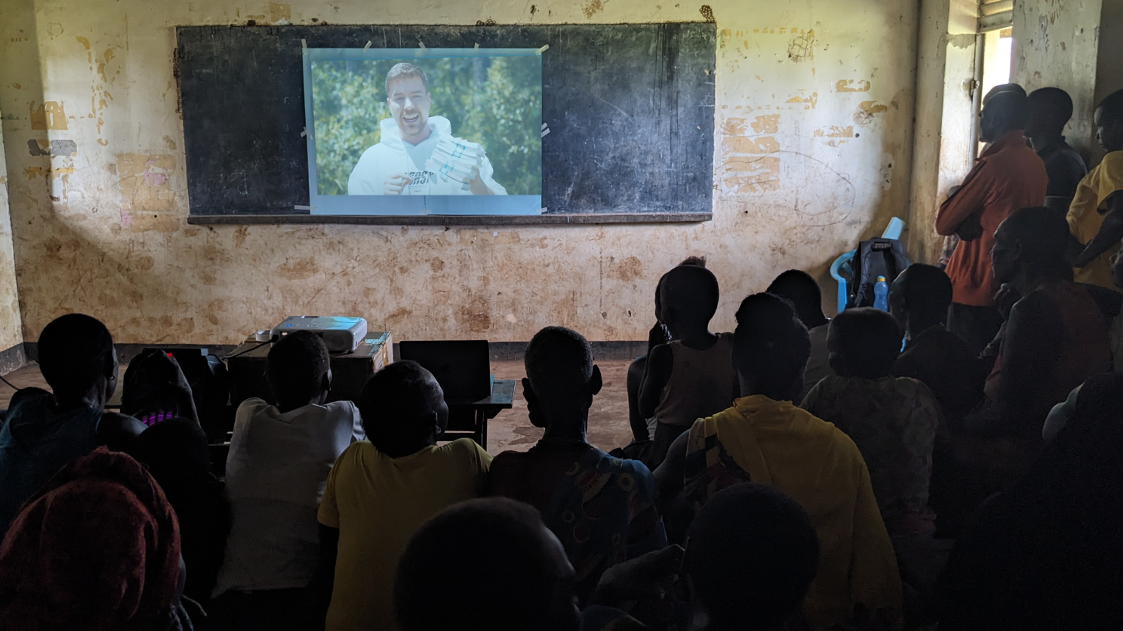 Villagers watch video projected onto a wall