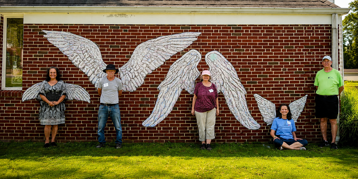 The finished Angel Wings mural at Westminster Presbyterian Church, with volunteers standing beneath the wings
