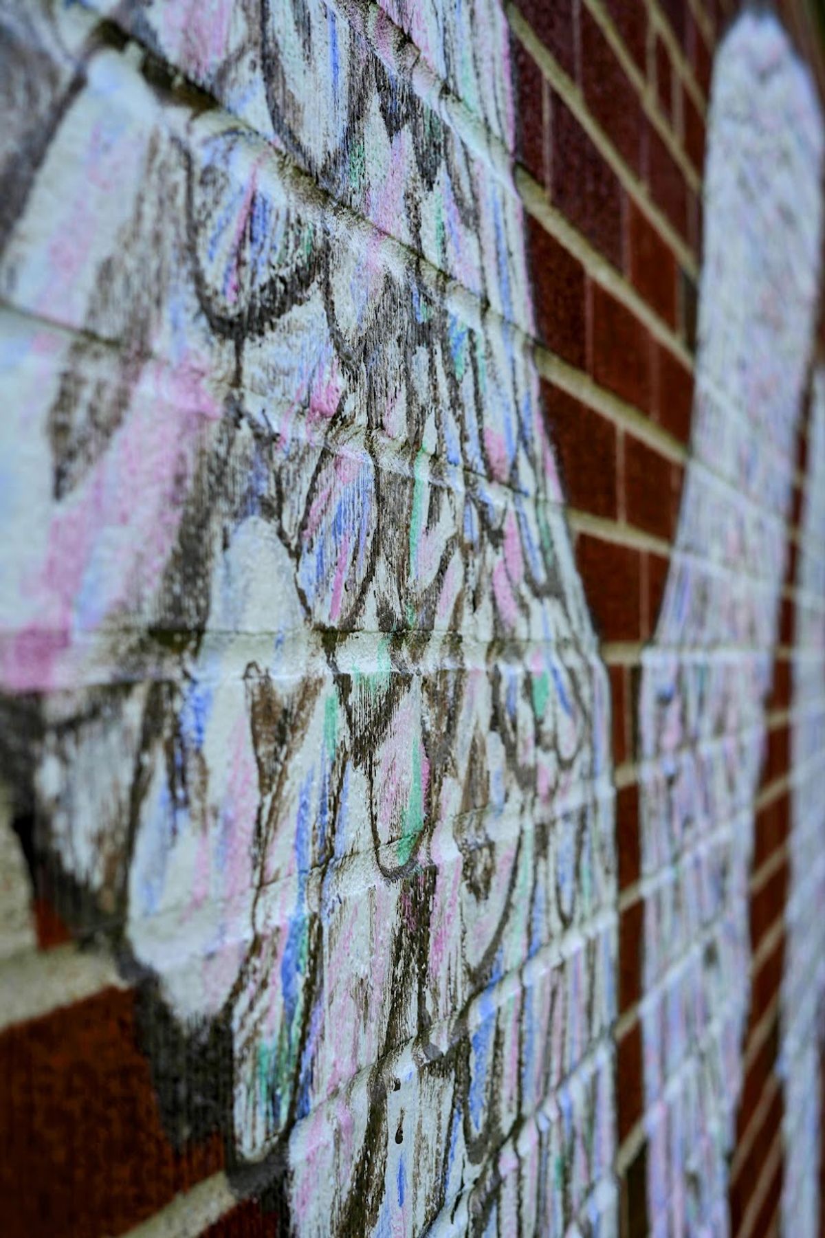 Chalk marks outlining feather shapes across the brick wall's mortar lines