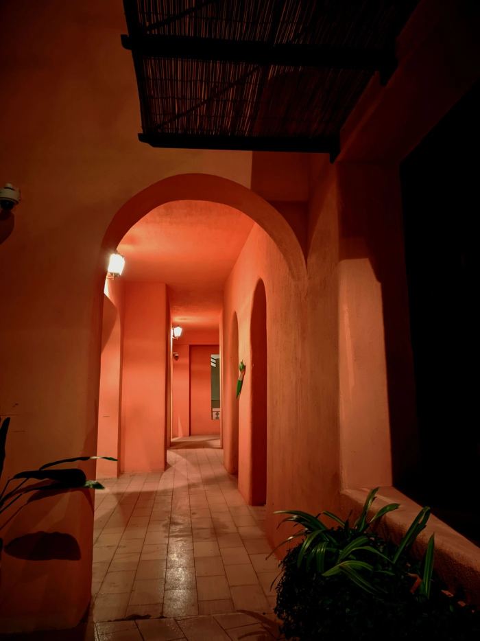 A corridor of terracotta plaster arches lit by a single wall lamp
