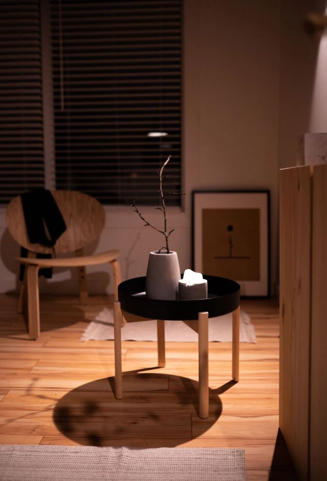 Rattan lounge chair and a black tray table in a warm, low-lit corner with framed art