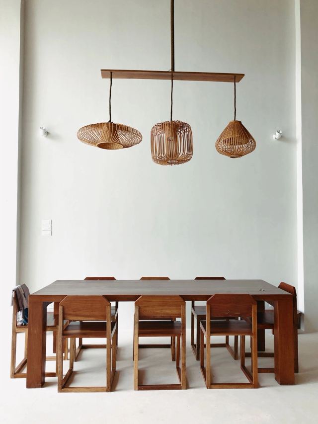 Oak dining table for eight beneath three woven rattan pendants
