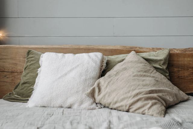 Linen and cotton cushions layered against a live-edge timber headboard