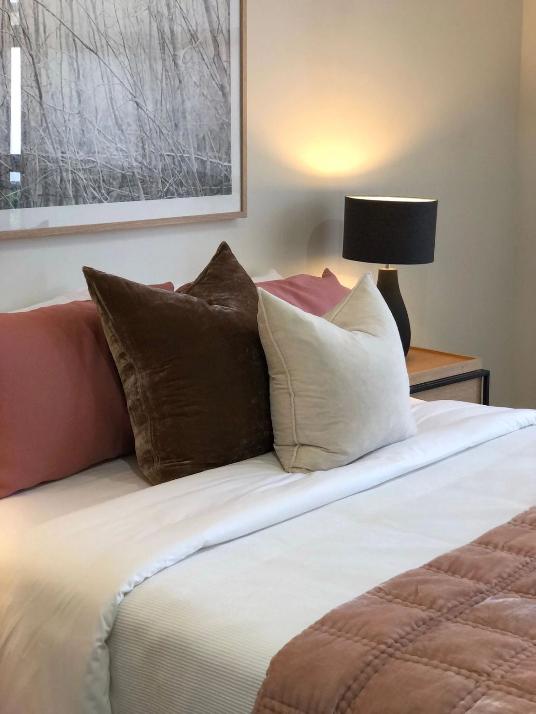Bed dressed in earth-toned linen with a black lamp