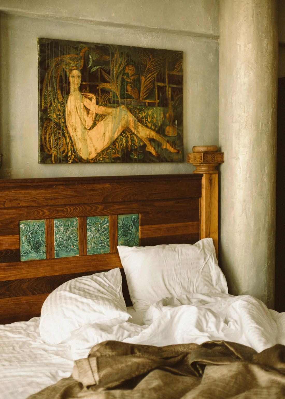 Bedroom with a carved wooden headboard and layered warm linen