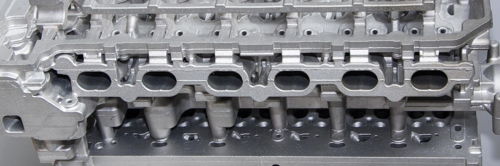 Bare aluminum die cast cylinder head showing intricate cast features and machined surfaces