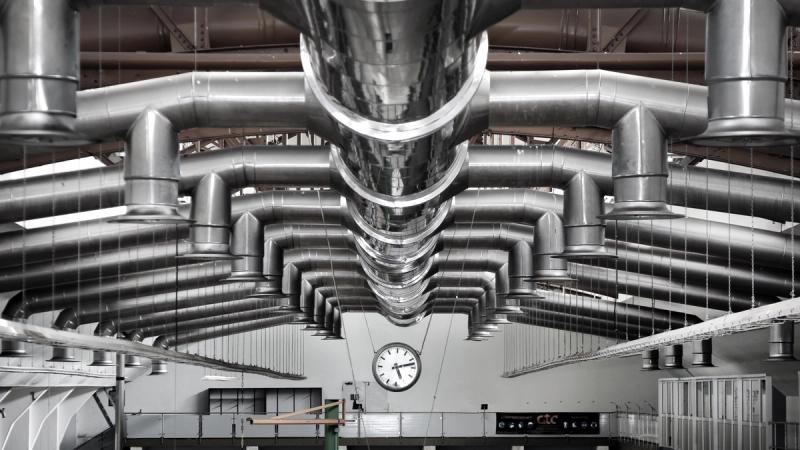Industrial ventilation and air treatment ductwork suspended from the ceiling of a manufacturing facility